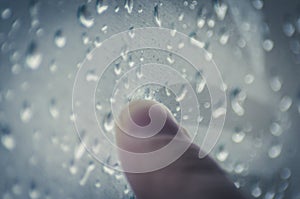 Moody Feelings Concept: Finger Of A Teenager Drawing On The Window With Raindrops On A Rainy Day