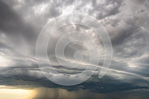 Moody landscape with dark stormy clouds with falling heavy downpour shower rain in summer