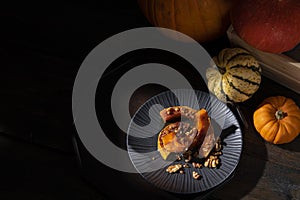 Moody pictorial still-life of roasted butternut squash pumpkin dusted with cinnamon, walnuts and honey
