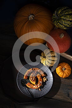 Moody pictorial still-life of roasted butternut squash pumpkin dusted with cinnamon, walnuts and honey