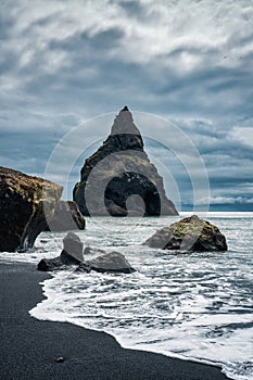 Moody Reynisdragar natural rock formation on Reynisfjara black sand beach in Atlantic ocean at Iceland