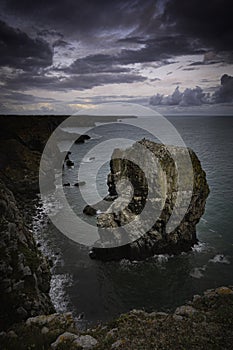 Moody sky over bay of water with sea stack on dramatic coast of Pembrokeshire in South Wales,UK