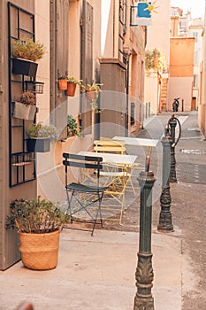 Moody street and outdoor chairs table flower pots, soft pastel colors. South France or Italy