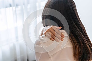 Moody young Asian woman feel neck pain while sitting on couch in living room. Health problem concept. Closeup, copy space