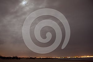 Moon Above Clouds Lights the Bright city Below