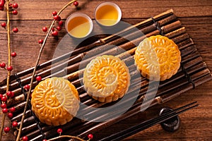 Moon cake Mooncake table setting - Round shaped Chinese traditional pastry with tea cups on wooden background, Mid-Autumn Festival