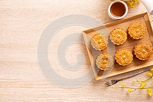 Moon cakes with tea on bright wooden table, holiday concept of Mid-Autumn festival traditional food layout design, top view, flat