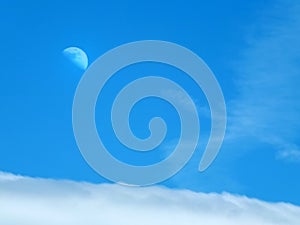 Moon and clouds in a blue summer daytime sky