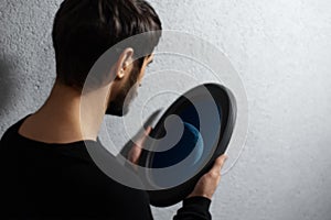 Moon inside black oval mirror frame, in male hands, on textured grey background. Contemporary artwork collage concept.