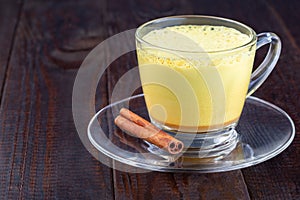 Moon milk with turmeric in a glass cup, horizontal, copy space