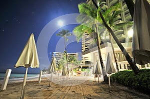 Moon over beach with umbrella's and trees