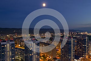 Moon over the city, high-rise buildings, night, mountains