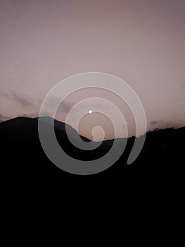 Moon over mountains in nightfall.