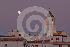 The moon, over a village, just before sunrise.