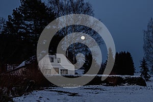 Moon peeping over the forest of an old farmhouse estate in a secluded place