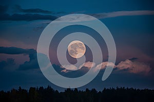 Moon peers through night sky with wisps of clouds