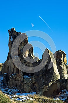 Moon and plane trail in the sky overhanging the lunar landscape of Cappadocia, Turkey