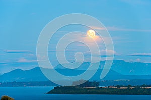 Moon rising between the clouds over Lake Llanquihue photo