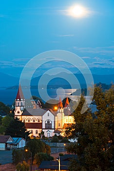 Moon rising between the clouds over Puerto Varas at the shores of Lake Llanquihue photo