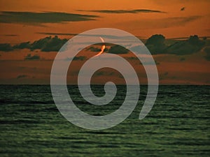 Moon set over sea observing and clouds after sunset