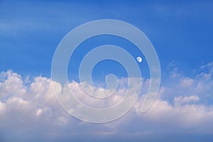 The moon in the sky in the daytime with the cloud against the blue sky background. Natural background