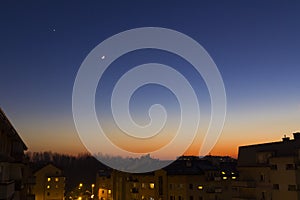 Moon and star in the evening over estate houses, falling asleep in the city