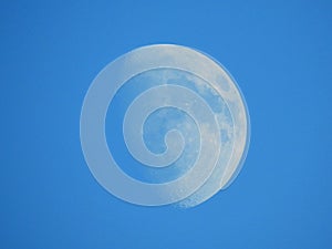 The moon visible in clear blue skies on a sunny December afternoon in the UK