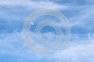 Moon Visible In Daylight Blue Sky With White Clouds