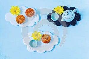 Mooncake, blue teapot, yellow chrysanthemum flowers on blue background. Chinese mid-autumn festival food