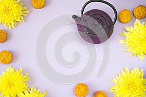 Mooncakes, tea, chrysanthemum flowers on light purple background with copy space. Chinese mid-autumn festival food.