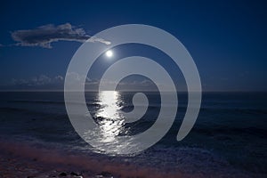 Moonlight path on water of Atlantic ocean at night on Tenerife and dark blue sky with full Moon and stars