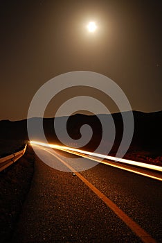 A moonlit road with car trails