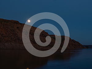 Moonrise over river with cliff