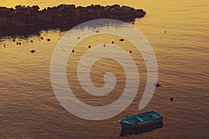 Moored blue fishing boat in the bay of Manarola village during sunset. Concept of landscape and nature. Manarola, Cinque Terre