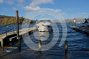 Moored boat at jetty, Lakeland fells backdrop. From Bowness-on Windermere, Cumbria