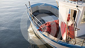 The moored fishing boat is lulled by the water while the sun reflects on the sea early in the morning with the winch of the