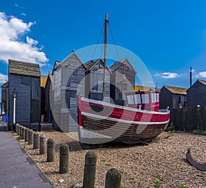 A moored fishing boat rests in front of the net drying sheds in the old town of at Hastings, Sussex, UK