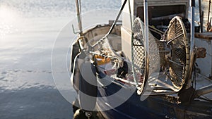 A moored fishing boat is waiting to set sail water while the sun reflects on the sea early in the morning with the winch of the