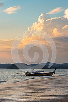 Moored thai traditional long-tail boat on shore at sunset on Ao nang beach in Krabi province