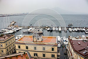 Moored yachtes and boats in port against Vesuvius volcano silhouette. Sailing and shiping concept.