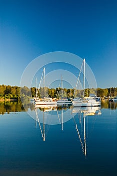 Moored yachts reflected against blue sky