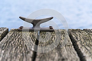 Mooring bollard of metal on a wooden pier bridge at the sea, cop