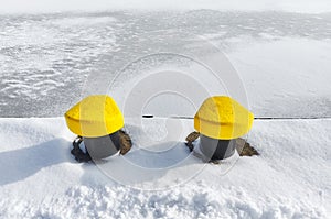 Mooring bollards on a pier by a frozen river