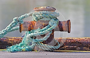 Mooring nautical bollard with green rope around it