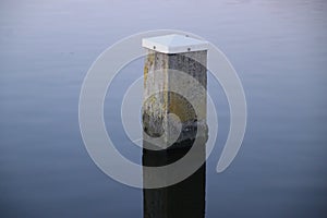 Mooring post reflecting in river Rotte at the Rottemeren in Zevenhuizen in the Netherlands