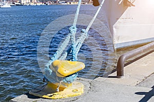 Mooring rope tied to the bollard at the pier.Nautical mooring rope. Shipping objects concept. Sailing ropes. Yellow marina bollard