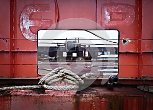 Mooring rope tied to a metal piling with a metal window opening at the dock