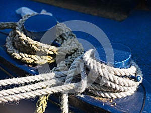 Mooring ropes tied to blue iron bollards of the boat