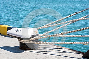 Mooring ropes are tied to the bollard. The ropes of the ship on the background of the sea.