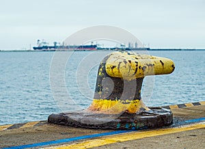 Mooring rusty cleat and cargo ship in the background